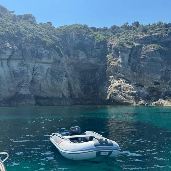 Annexe du voilier posée sur les eaux turquoise face aux grottes aux pigeons du Cap Corse