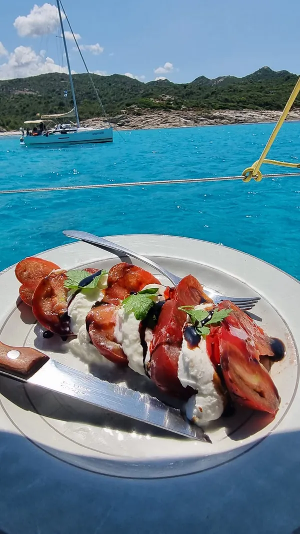 Salade de tomates mozzarella servie à bord face au mouillage turquoise des Agriates