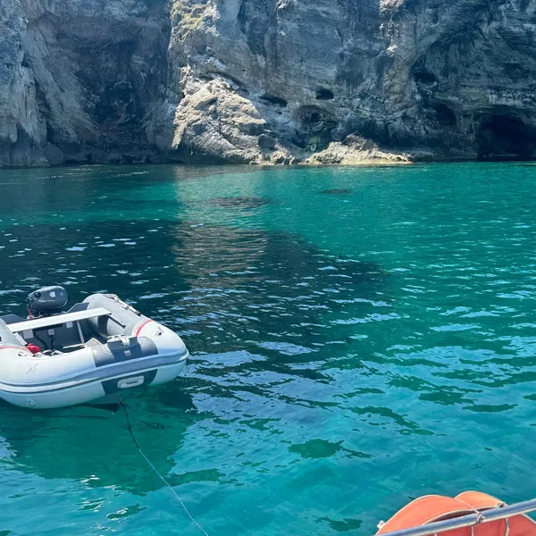 Mouillage aux grottes aux pigeons vu depuis le voilier, annexe et falaise en arrière-plan