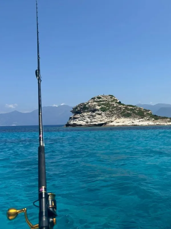Pêche à la canne depuis le voilier face à un îlot rocheux corse
