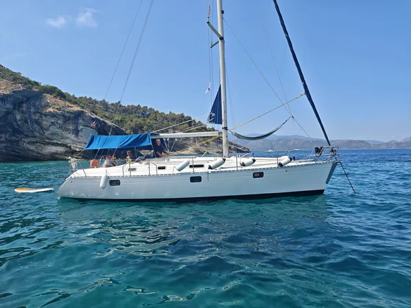 Le skipper Stan à la barre du voilier au mouillage devant le Cap Corse, panorama sur les montagnes