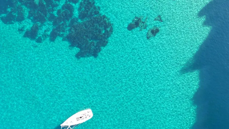 Voilier privatisé vu du ciel sur une eau turquoise cristalline