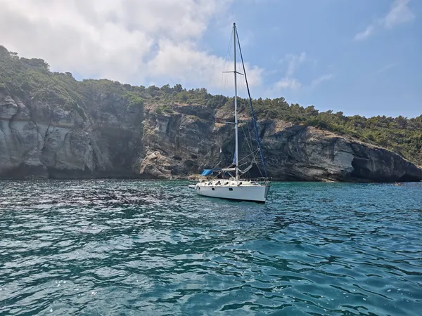 Voilier Eridu au mouillage, vue large sur les falaises et les grottes aux pigeons du Cap Corse